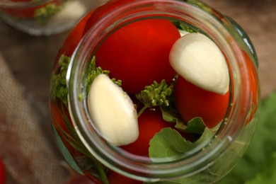 Glass jar with vegetables, herbs and brine on table, closeup