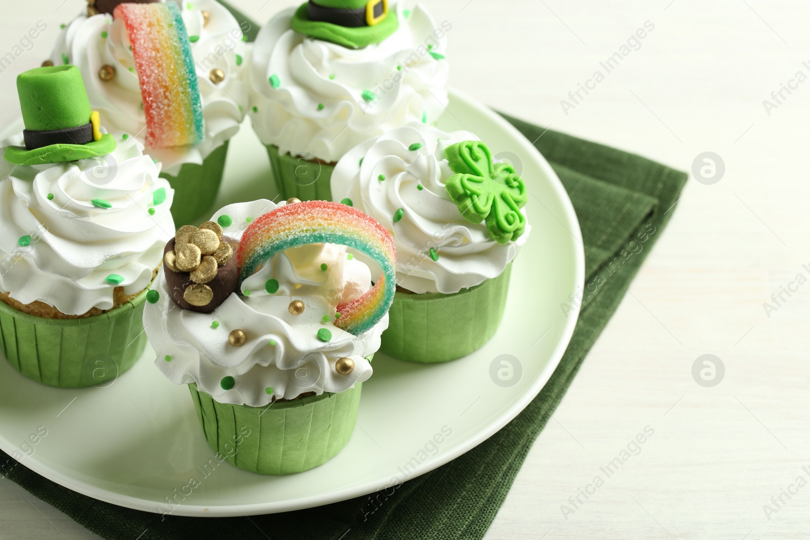 Photo of St. Patrick's day party. Tasty festively decorated cupcakes on white table, closeup