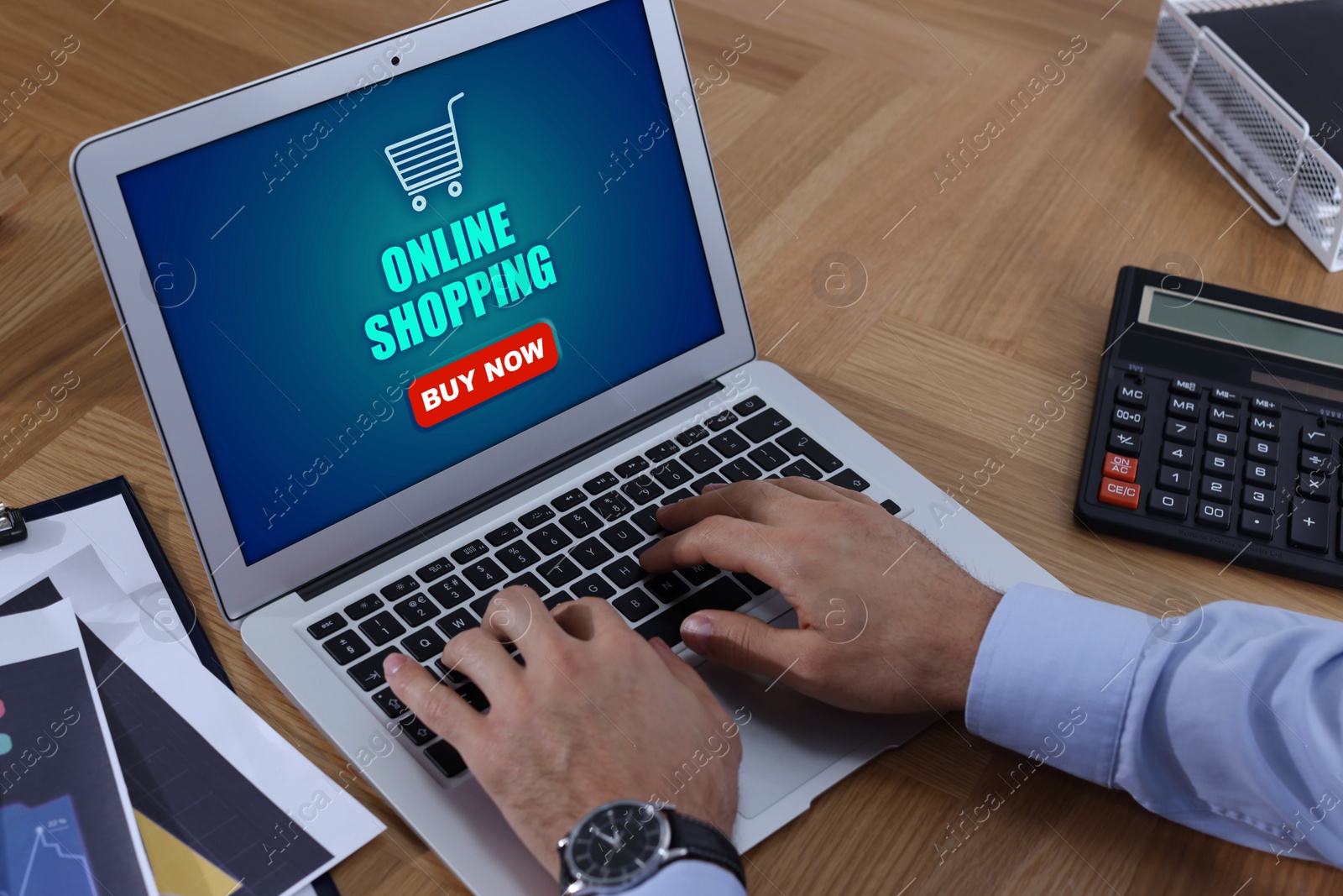 Image of Man using laptop for online shopping at wooden table, closeup