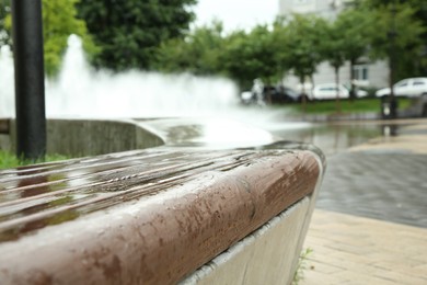 Photo of Wooden bench with water drops outdoors, closeup. Rainy weather