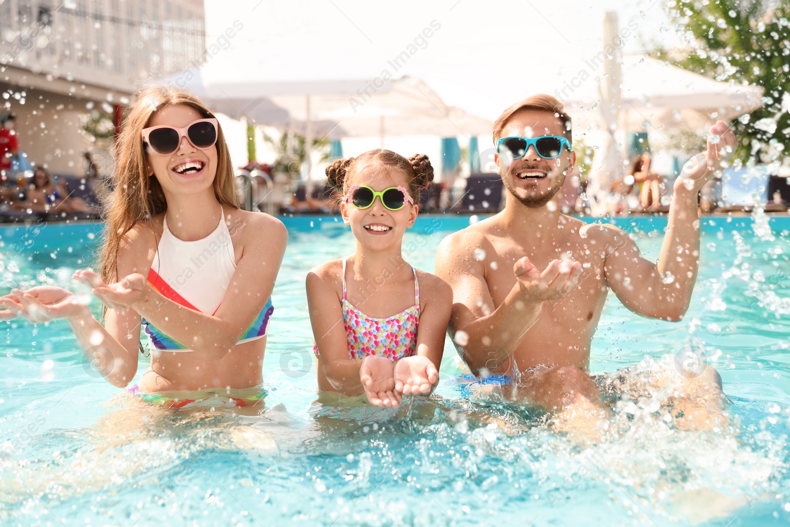 Photo of Happy family having fun in pool on sunny day