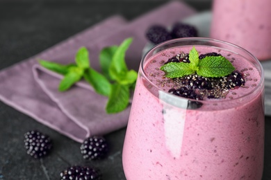 Delicious blackberry smoothie in glassware on black table, closeup