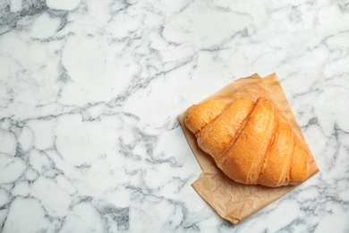 Tasty croissant on marble background, top view