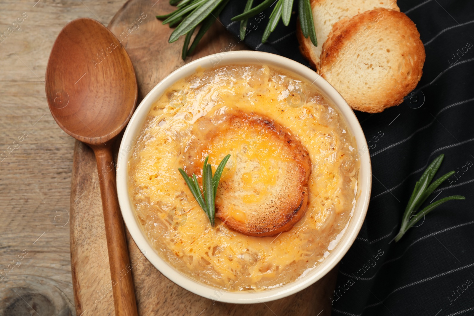 Photo of Tasty homemade french onion soup served on wooden table, flat lay