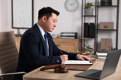 Photo of Notary writing notes at wooden table in office