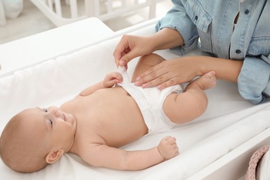 Mother changing her baby's diaper on table at home