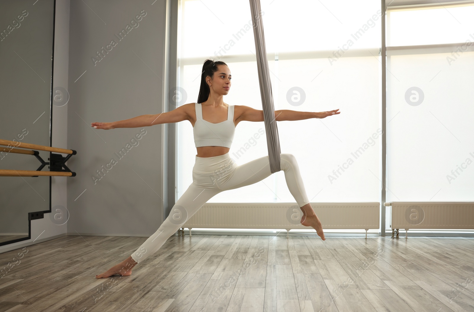 Photo of Young woman with hammock practicing fly yoga in studio