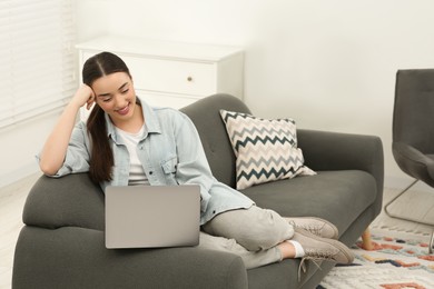 Photo of Woman using laptop on couch at home