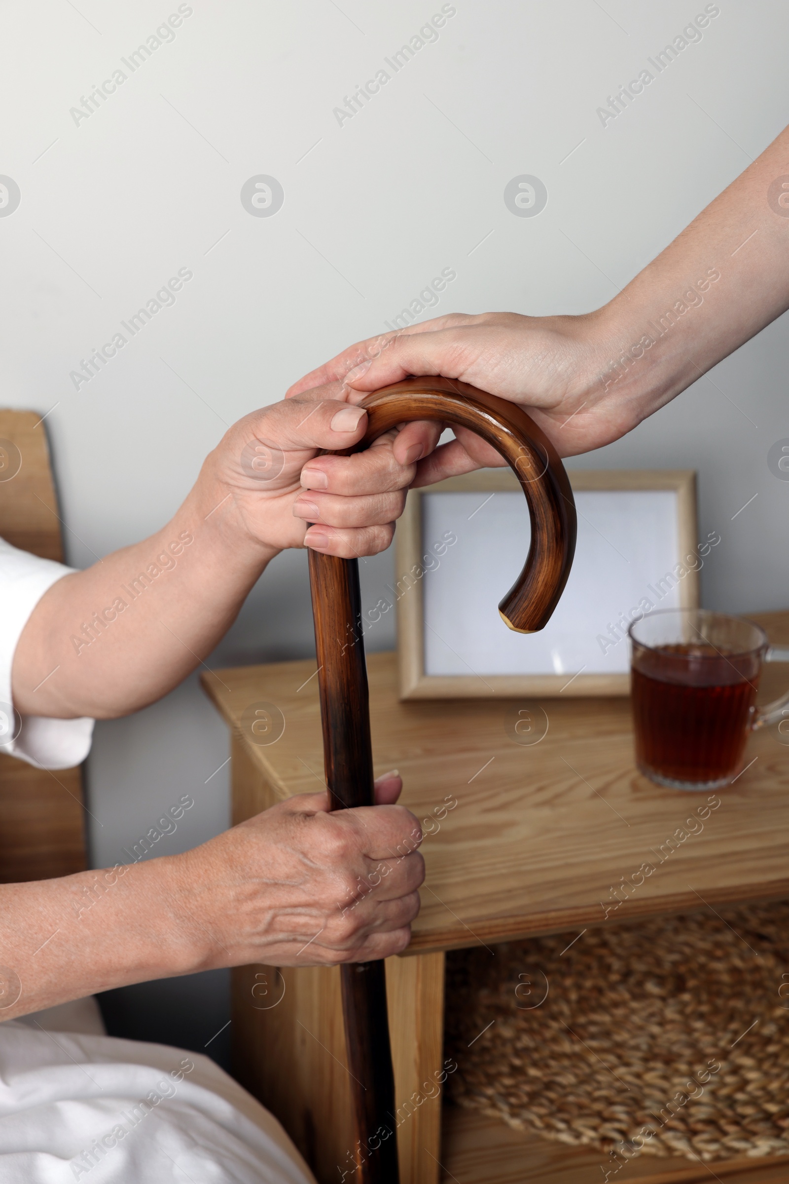 Photo of Caregiver and elderly woman with walking cane at home, closeup