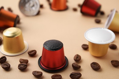 Photo of Many coffee capsules and beans on beige background, closeup. Space for text