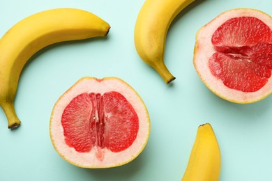 Photo of Bananas and halves of grapefruit on turquoise background, flat lay. Sex concept