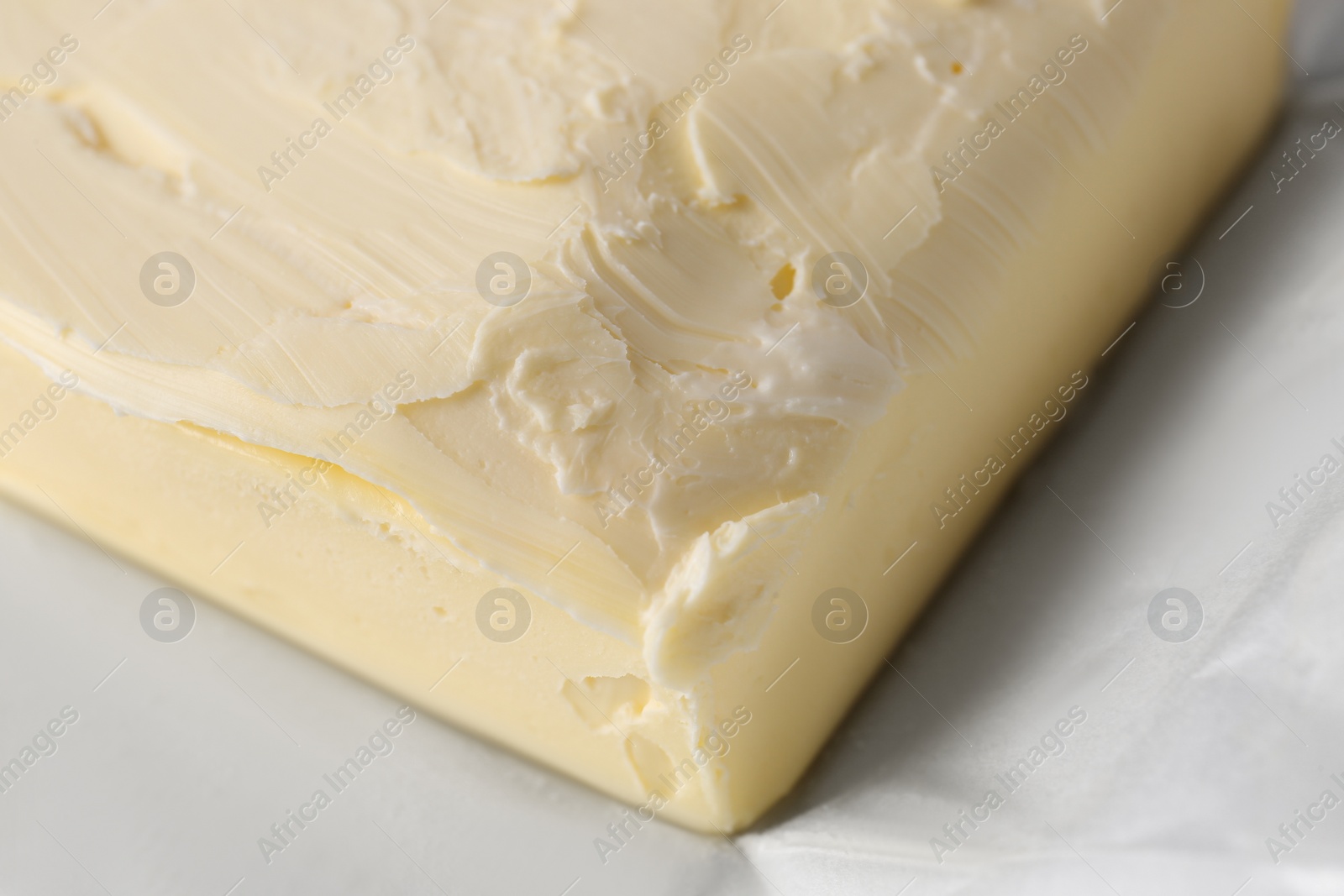 Photo of Piece of tasty homemade butter on paper wrap, closeup