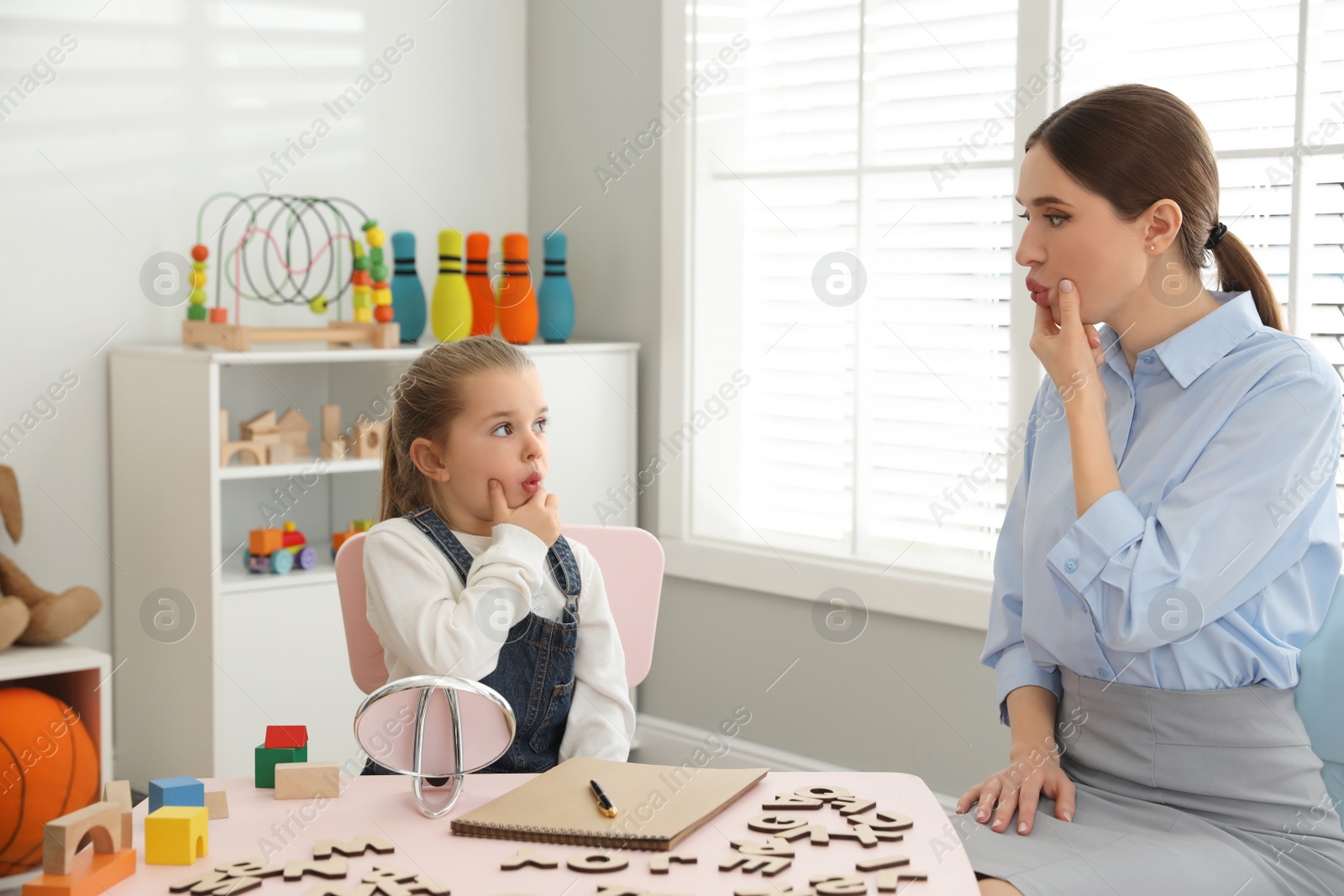 Photo of Speech therapist working with little girl in office