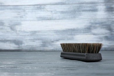 Photo of Shoe brush on grey wooden table, space for text. Footwear care item