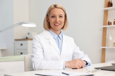 Photo of Portrait of happy dermatologist at white table in clinic