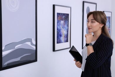 Photo of Thoughtful young woman with tablet at exhibition in art gallery