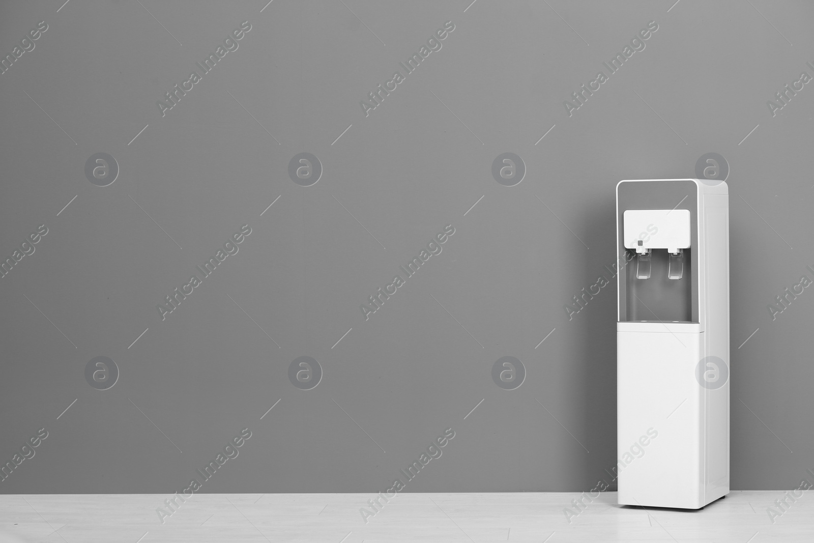 Photo of Modern water cooler against gray wall with space for text