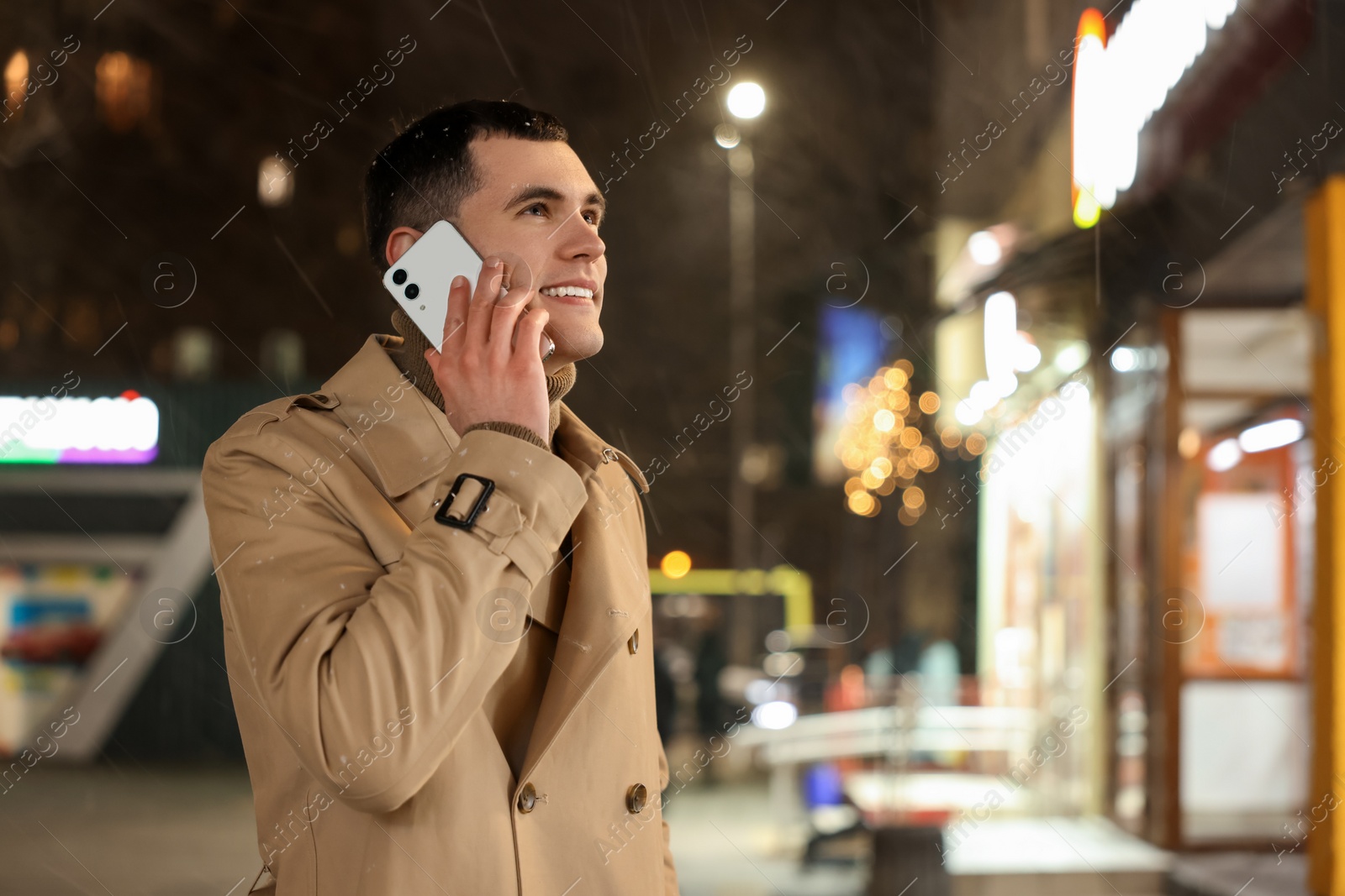 Photo of Man talking by smartphone on night city street, space for text