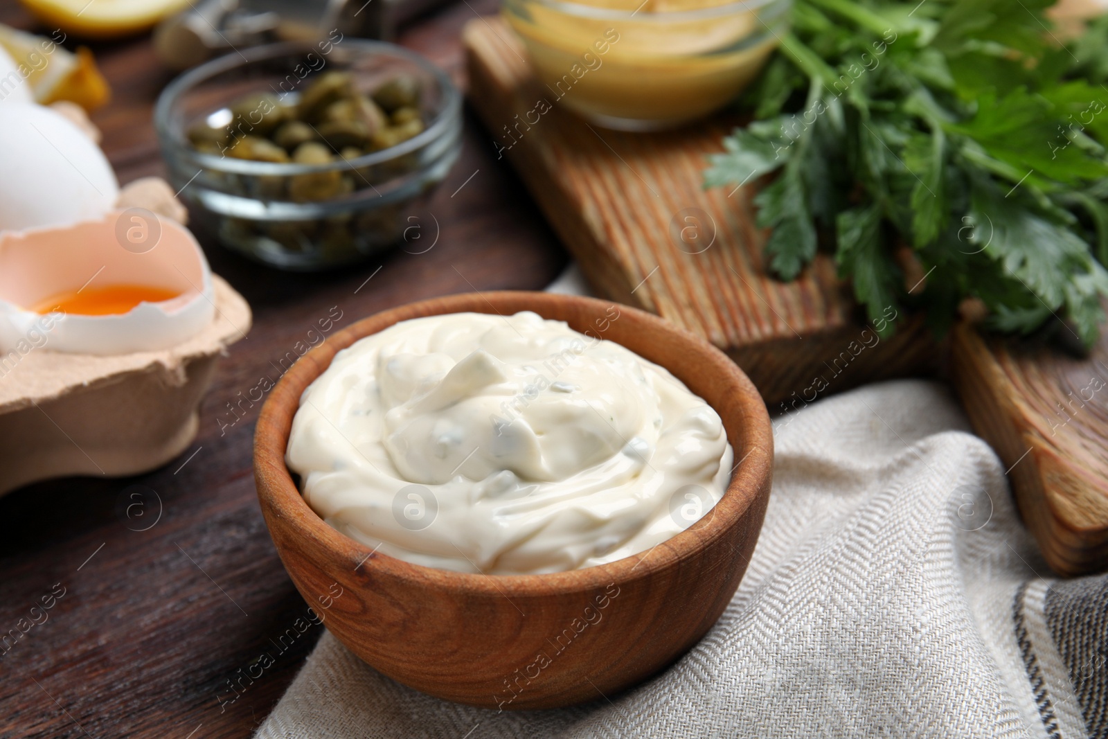 Photo of Tasty tartar sauce and ingredients on wooden table