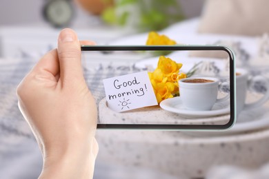 Image of Woman taking picture of aromatic coffee, flowers and card with phrase GOOD MORNING! on tray, closeup