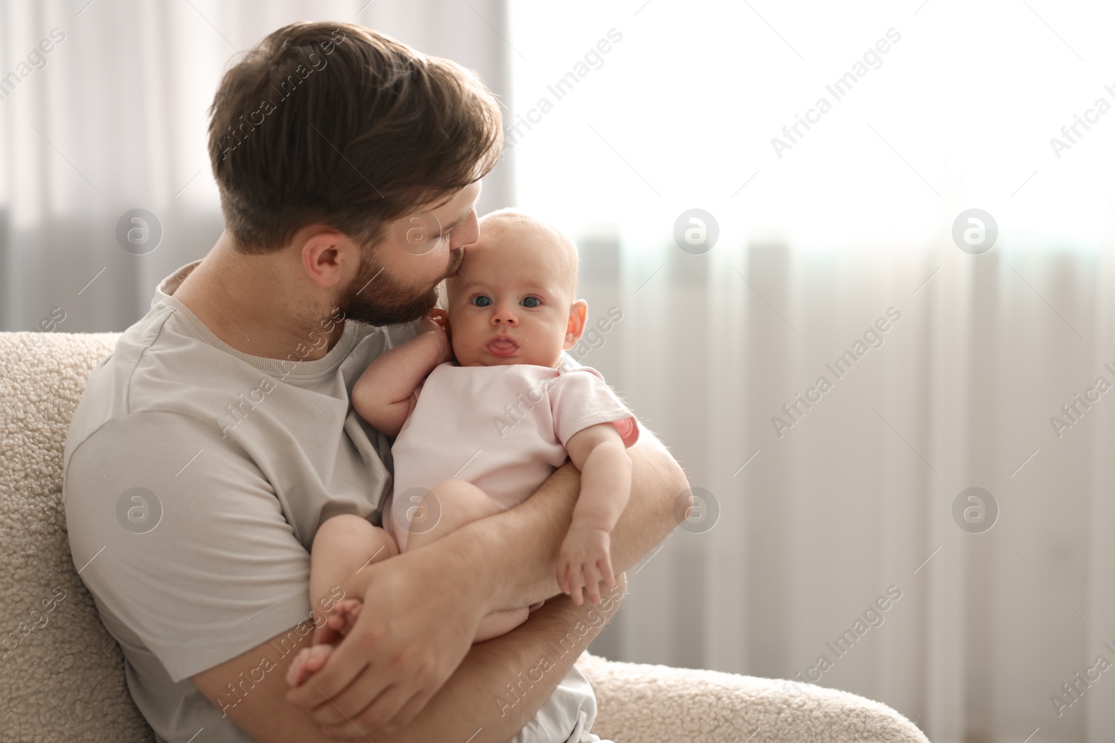 Photo of Father with his cute baby in armchair at home, space for text