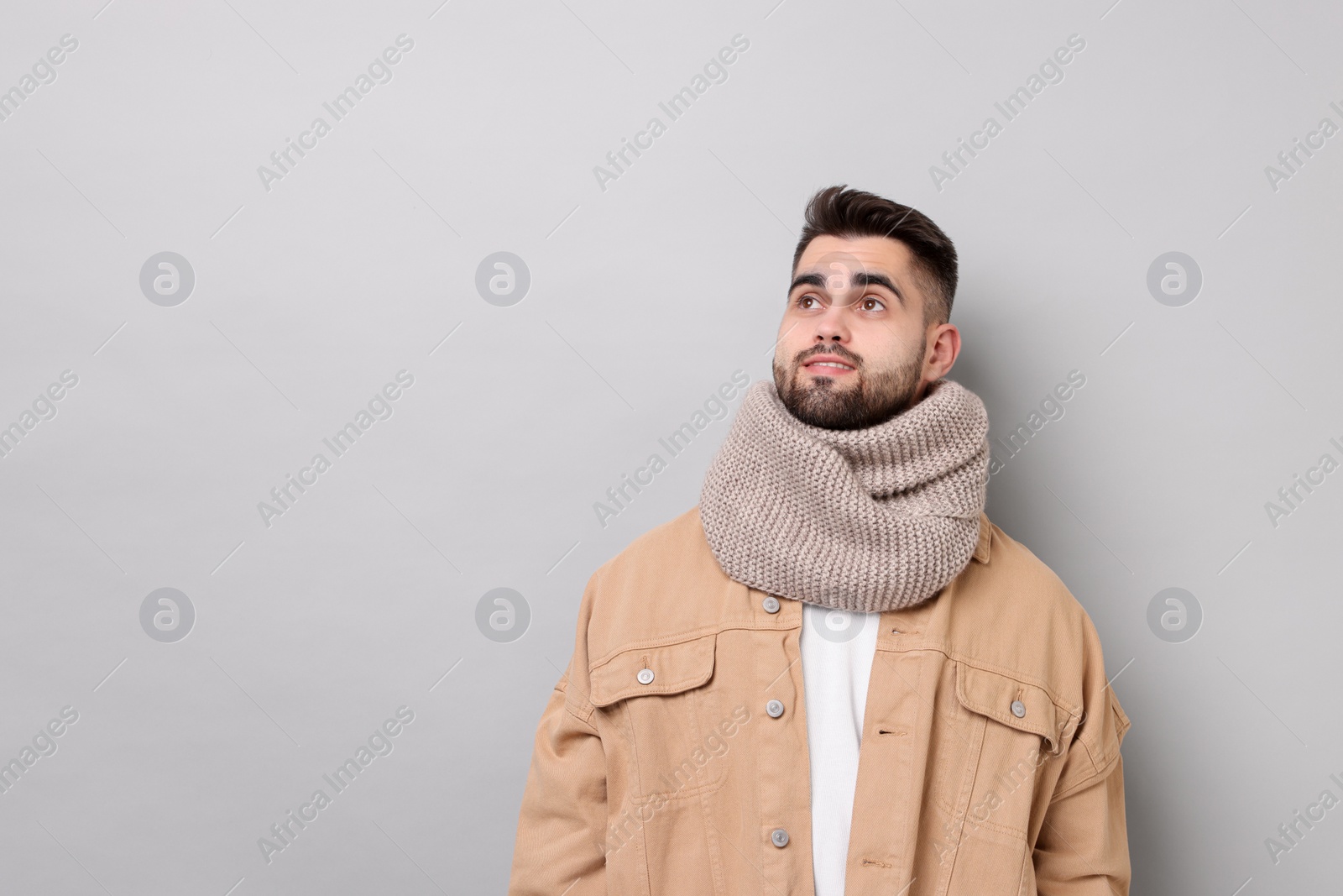 Photo of Handsome man in warm scarf on light grey background. Space for text