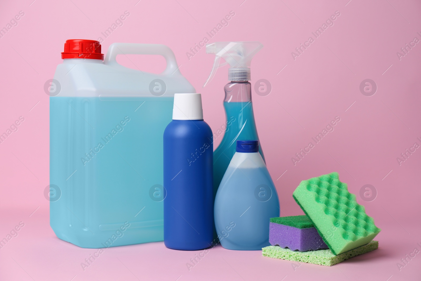 Photo of Bottles of different detergents and tools on pink background. Cleaning supplies