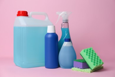 Photo of Bottles of different detergents and tools on pink background. Cleaning supplies
