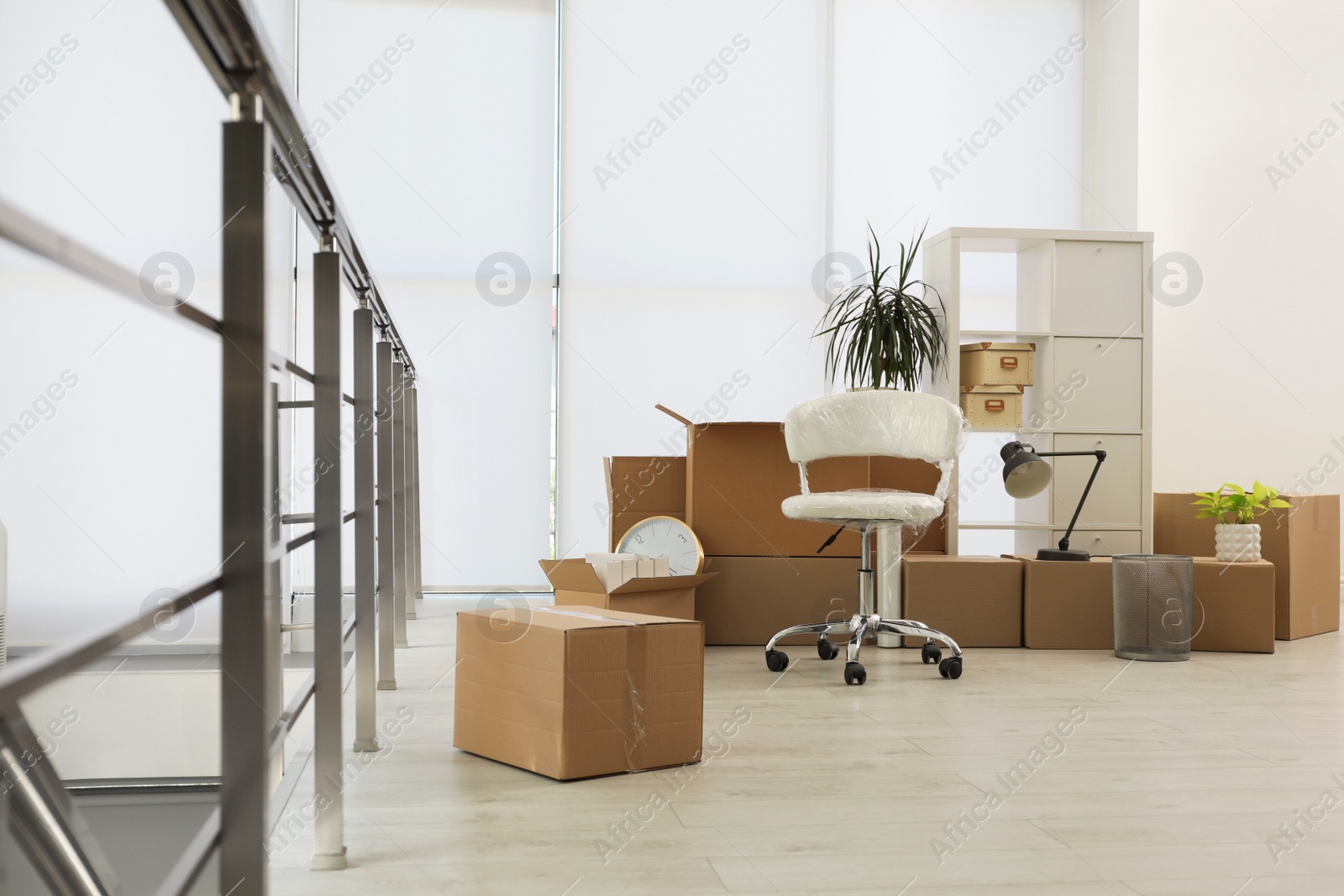 Photo of Cardboard boxes with packed stuff in new office. Moving day