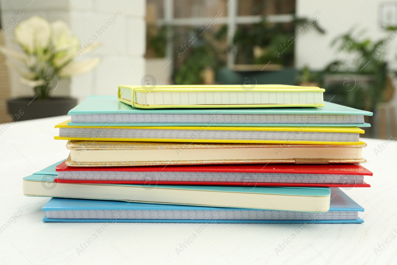 Photo of Stack of colorful planners on white wooden table indoors