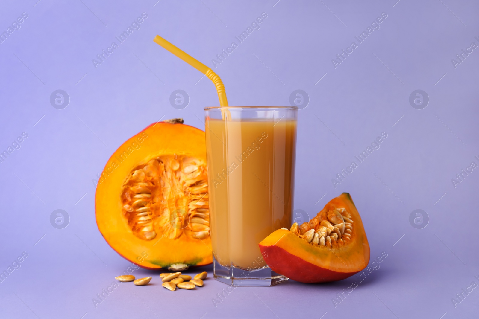 Photo of Tasty pumpkin juice in glass and cut pumpkin on lavender color background