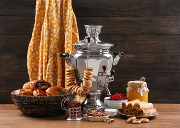 Photo of Traditional Russian samovar and treats on wooden table