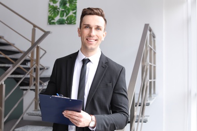 Male real estate agent with clipboard indoors