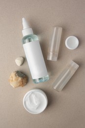 Different cosmetic products and stones on beige background, flat lay