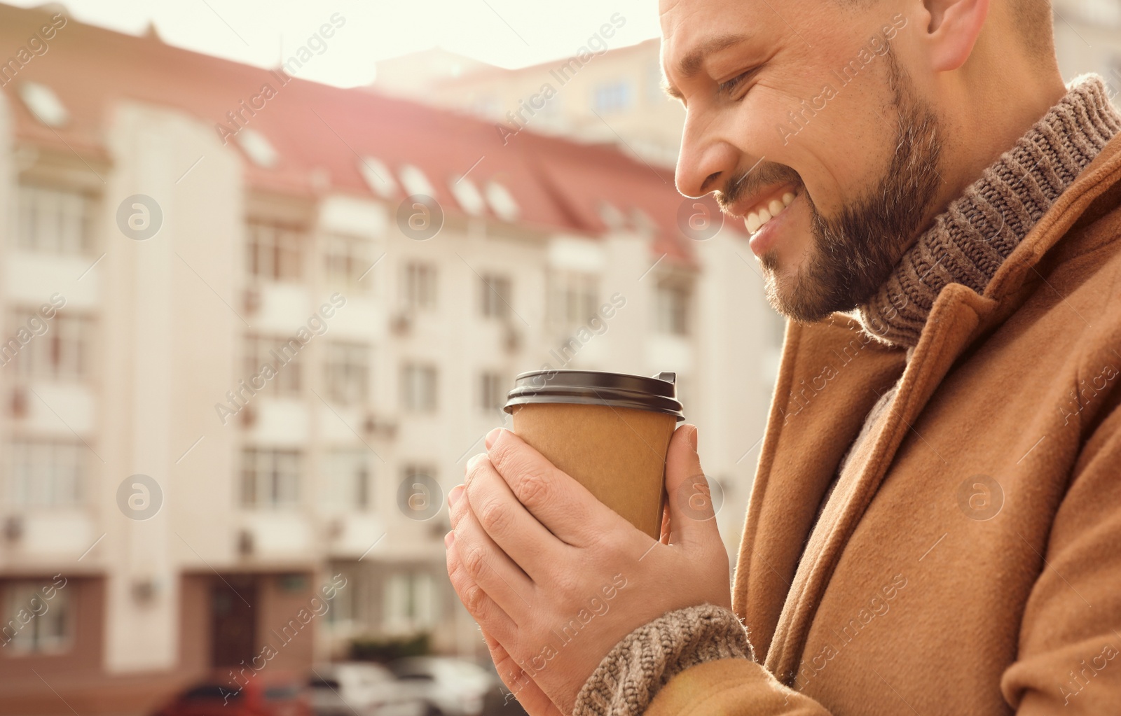 Photo of Man with cup of coffee on city street in morning