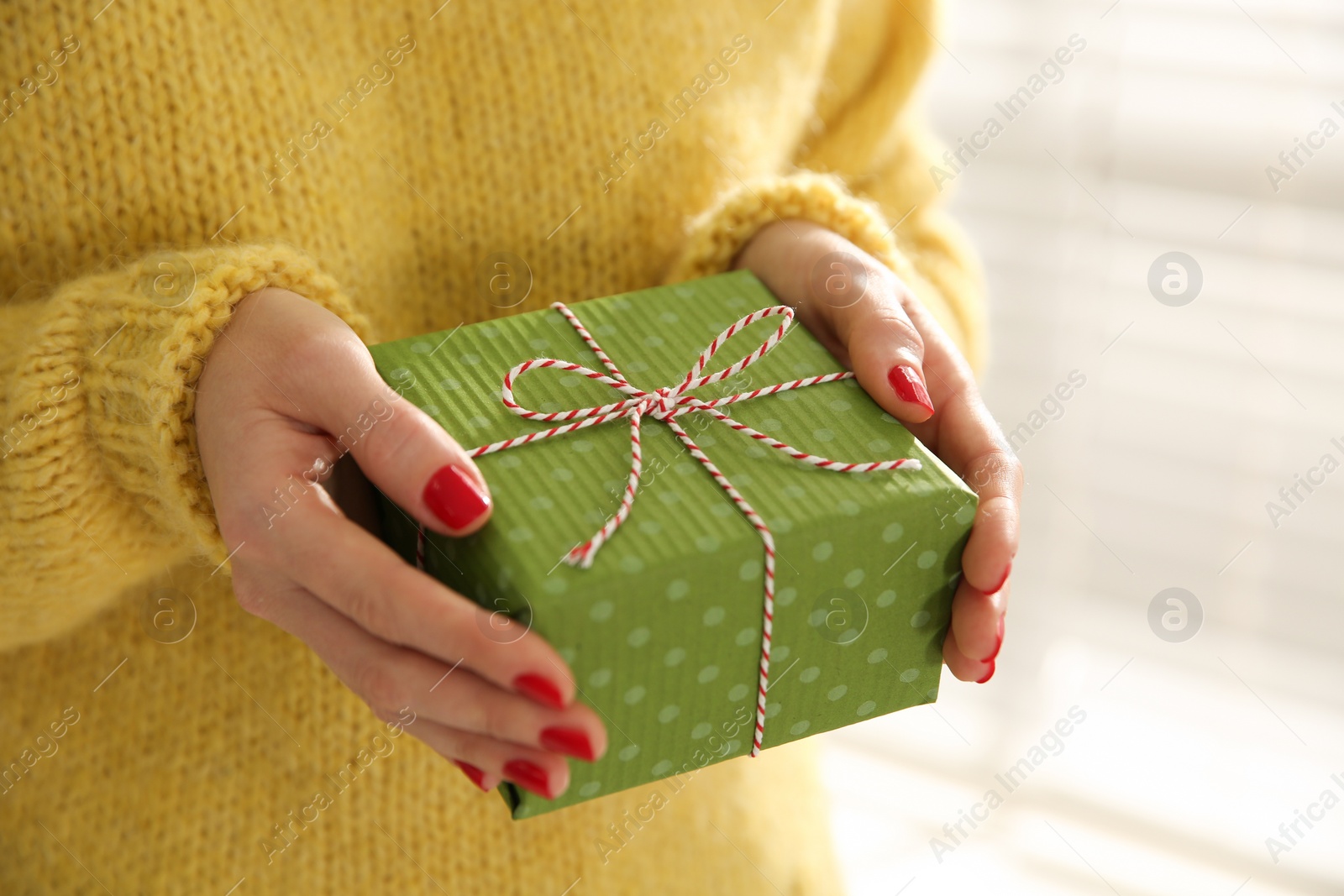 Photo of Woman holding Christmas gift box indoors, closeup