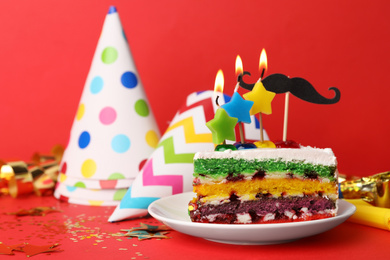 Piece of birthday cake with candles on red background, space for text