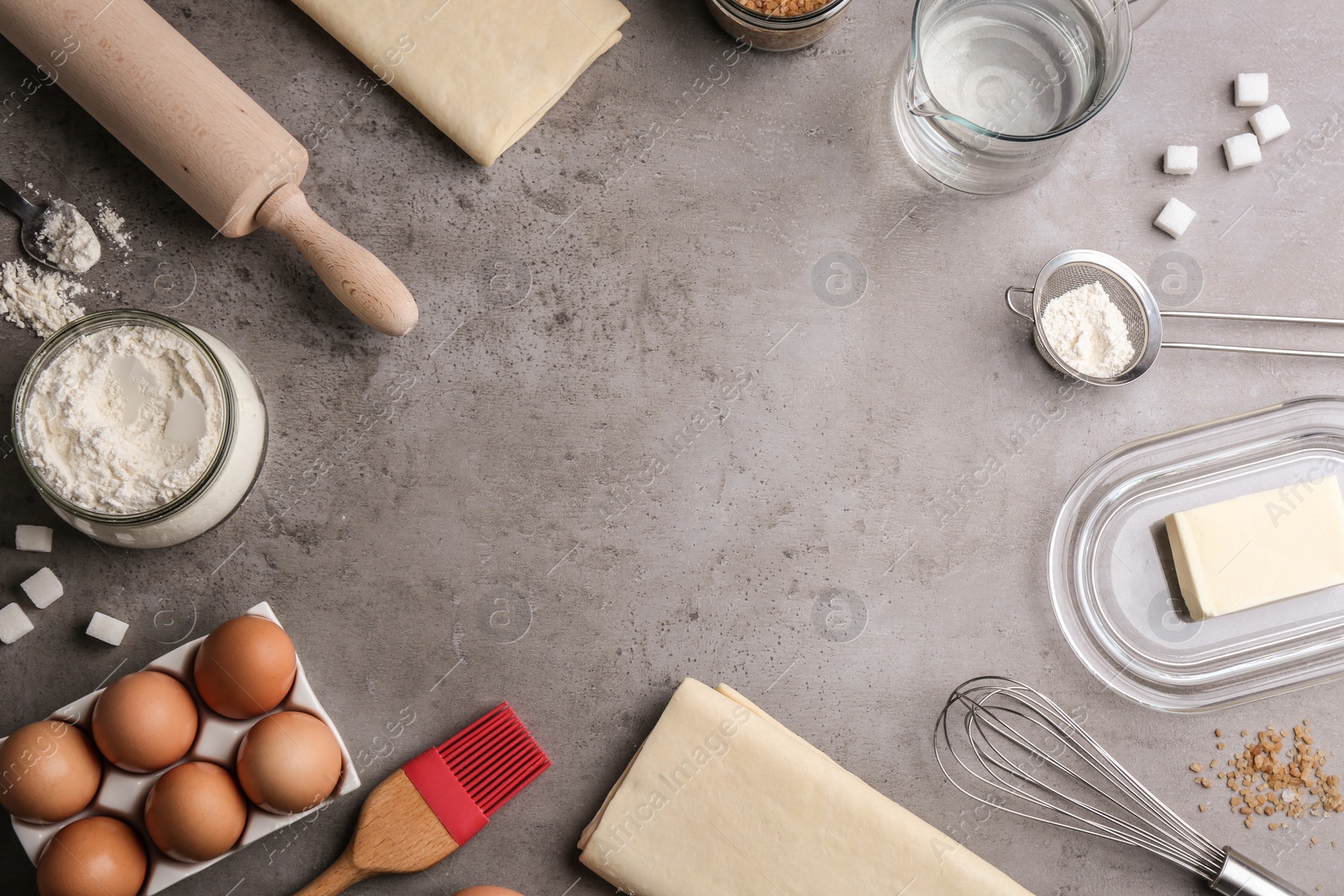 Photo of Flat lay composition with fresh dough on grey table, space for text. Puff pastry