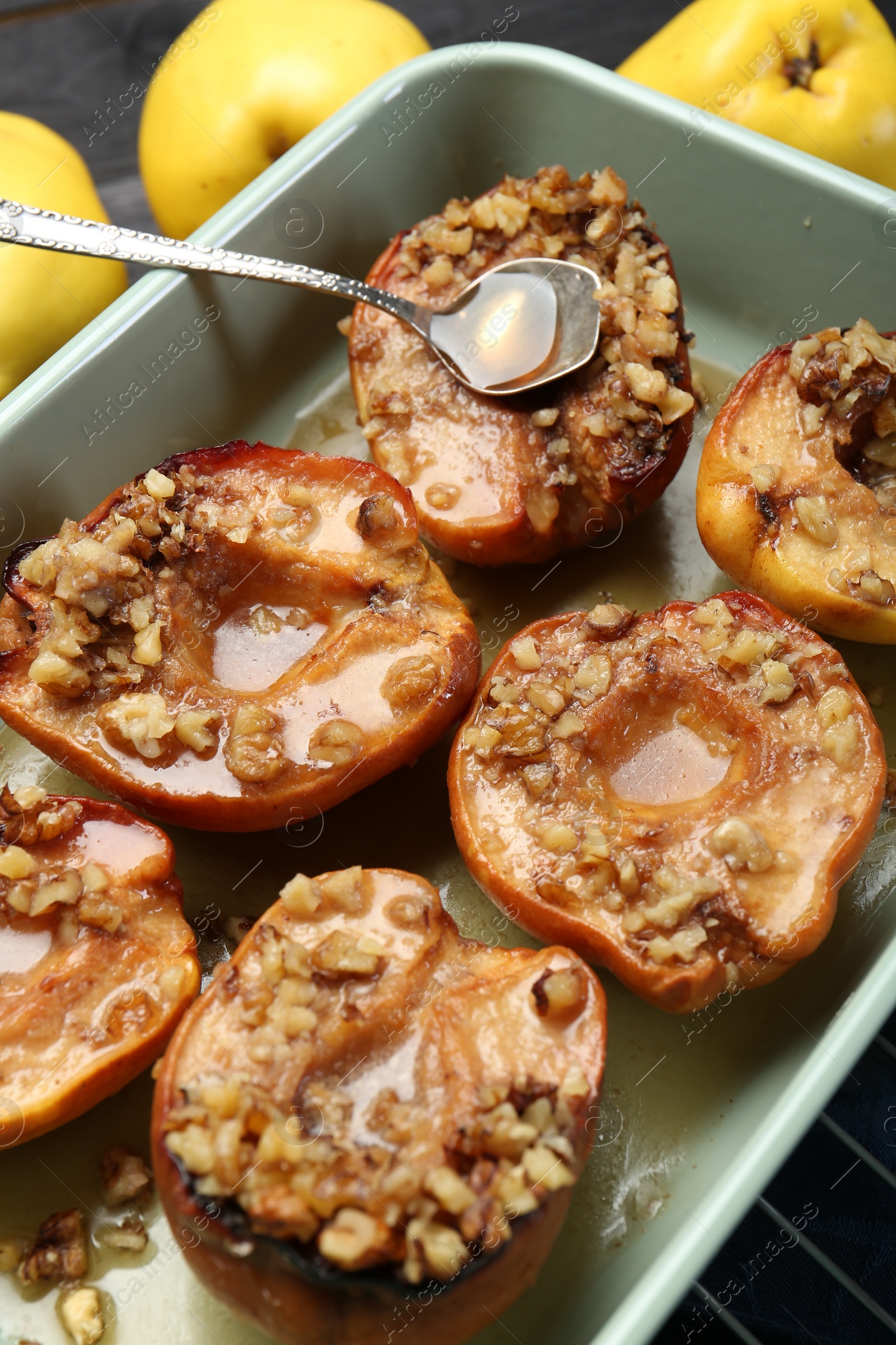 Photo of Tasty baked quinces with nuts and honey in dish on grid, closeup