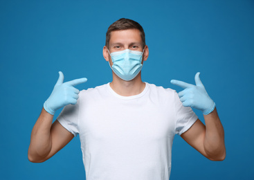 Photo of Male volunteer in mask and gloves on blue background. Protective measures during coronavirus quarantine