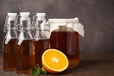 Photo of Tasty kombucha, mint and orange on wooden table