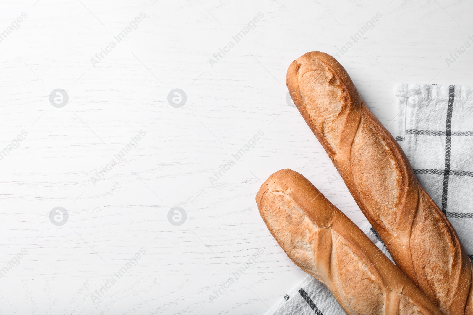 Photo of Tasty baguettes on white wooden table, flat lay. Space for text