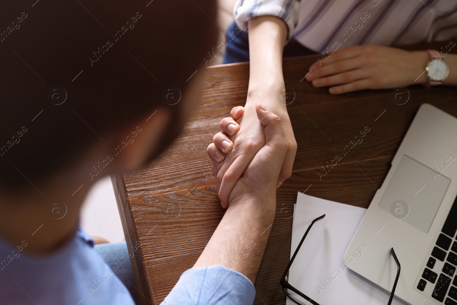 Photo of Business partners shaking hands at table after meeting in office, closeup