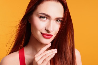 Photo of Beautiful woman with red dyed hair on orange background