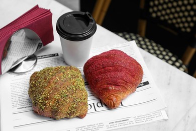 Delicious croissants and paper cup of coffee on white table