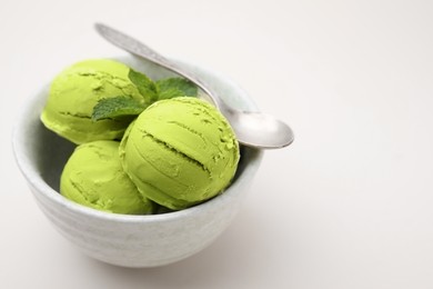 Tasty matcha ice cream and spoon in bowl on beige table, closeup. Space for text