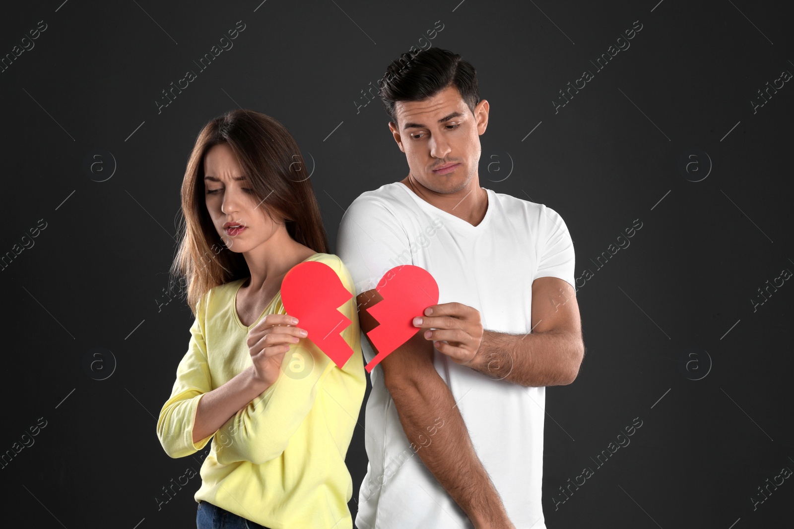 Photo of Couple with torn paper heart on black background. Relationship problems