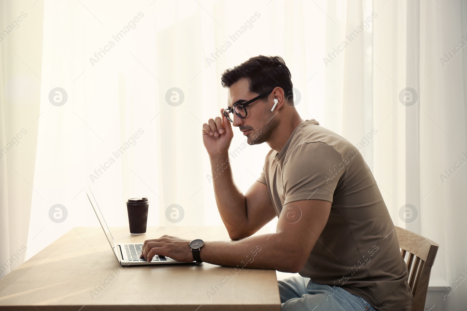 Photo of Portrait of young man with laptop at table indoors