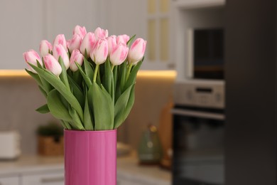 Beautiful bouquet of fresh pink tulips in kitchen. Space for text