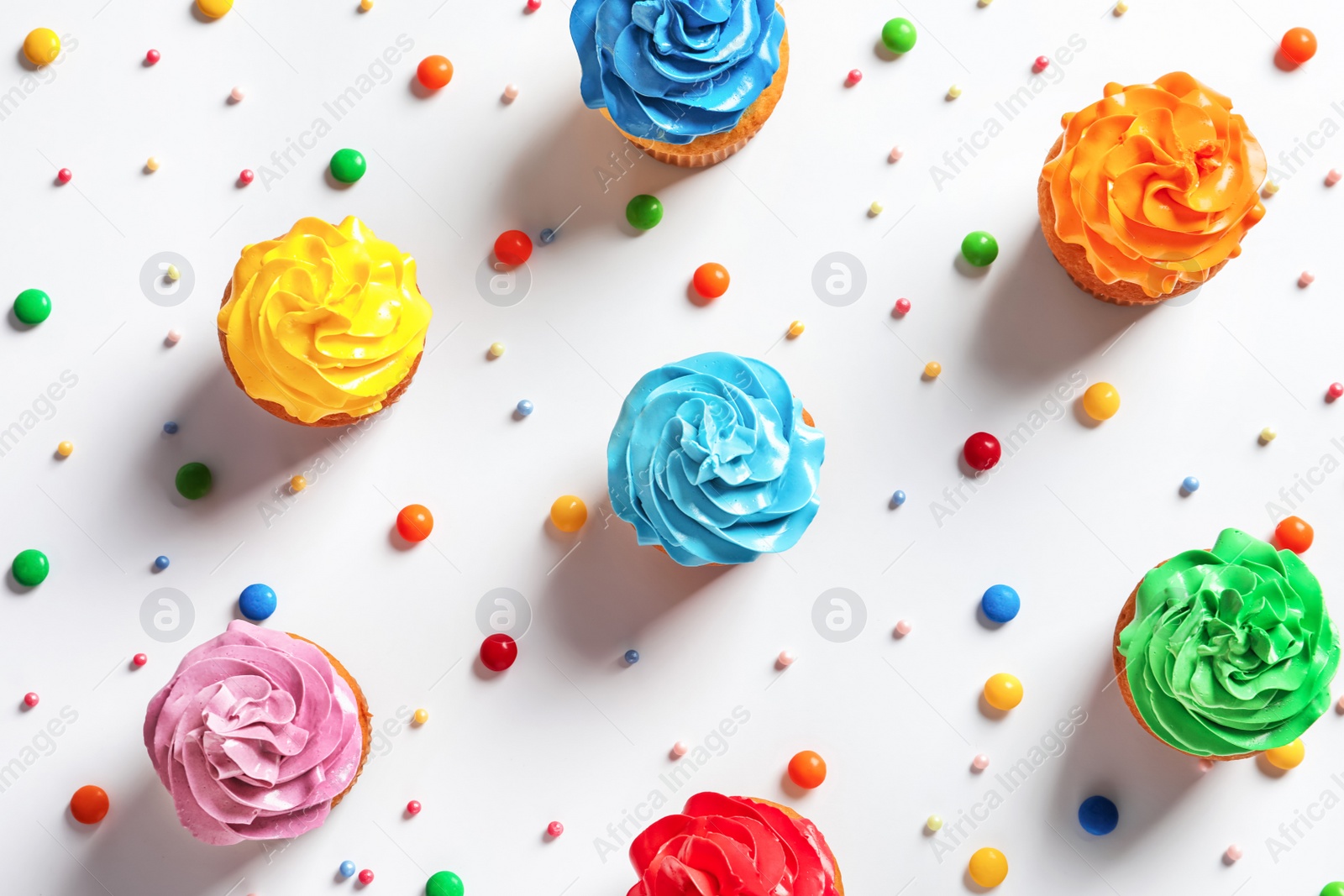 Photo of Flat lay composition with colorful birthday cupcakes on light background